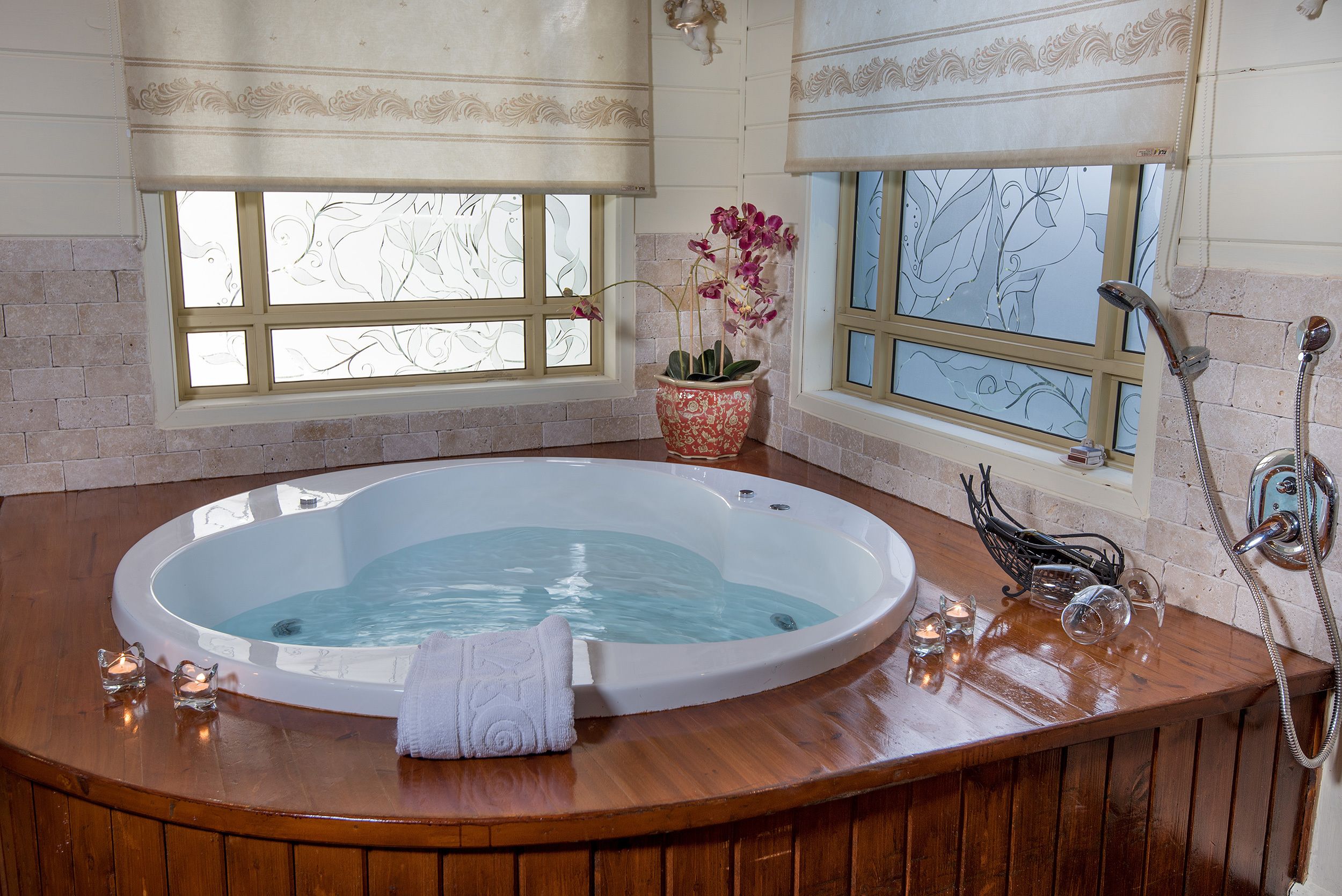 Baño con bañera de madera, una orquídea en maceta y una ducha.