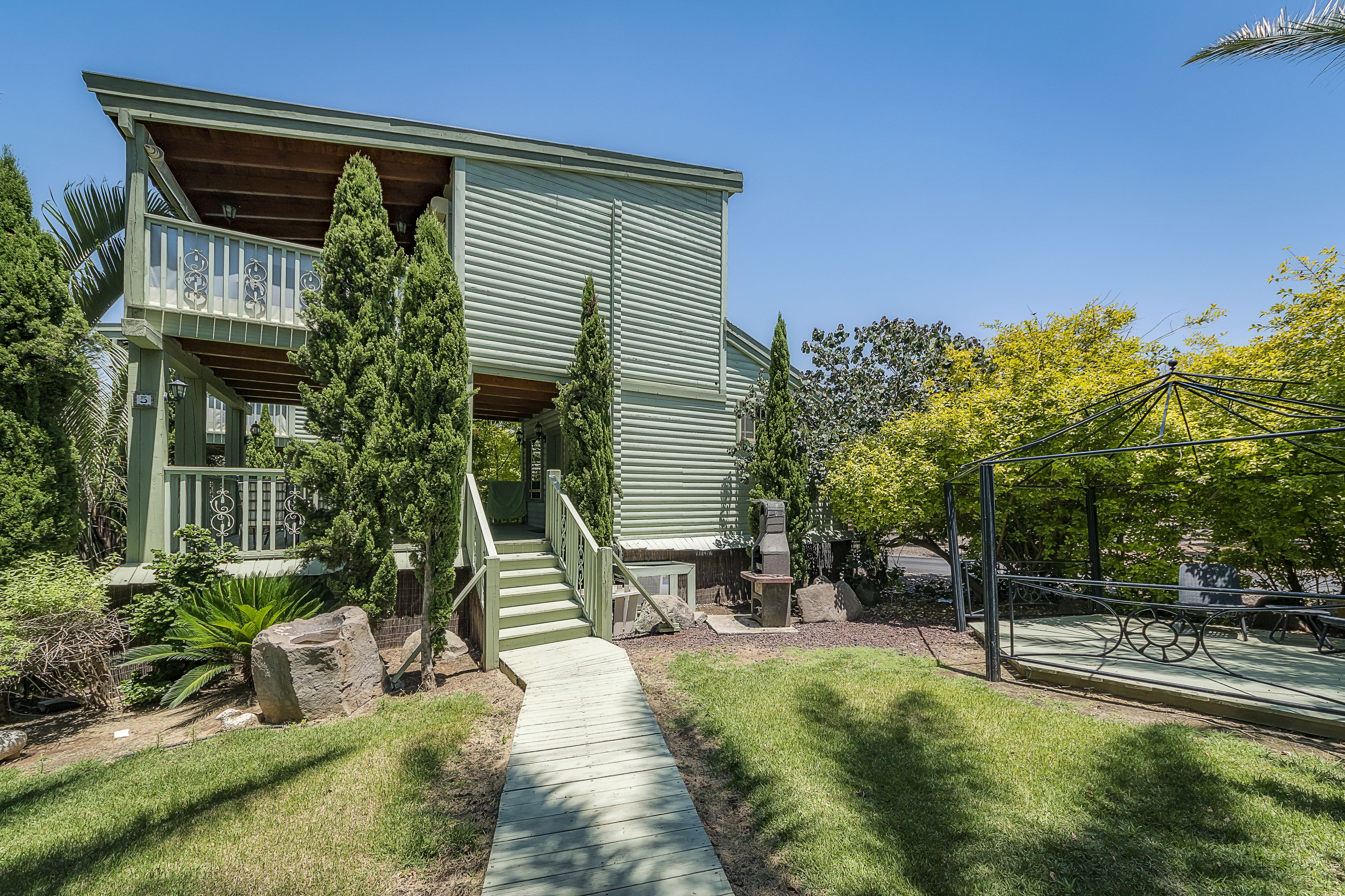 A two-story building with a green exterior, a wooden deck, and a stone pathway leading to the entrance.