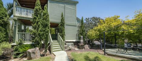 A two-story building with a green exterior, a wooden deck, and a stone pathway leading to the entrance.