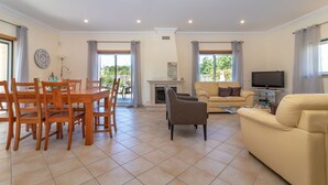 Una sala de estar con un sofá, un televisor y una chimenea. Hay un comedor con una mesa y sillas.
