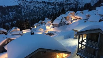 A snow-covered village with houses and a wooden structure with a balcony.