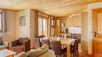 Un ambiente accogliente con zona pranzo, soffitto in legno e cucina sullo sfondo.