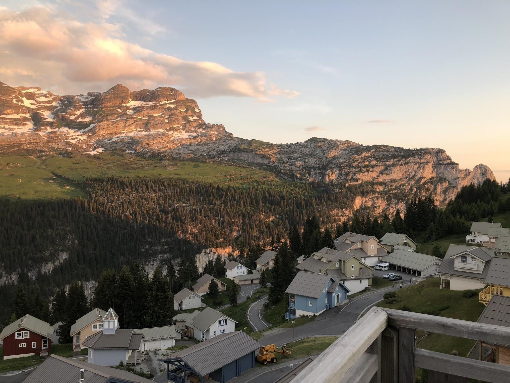 A residential area with houses, a road, and a mountain range in the background.