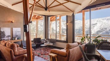 A cozy lounge area with leather sofas, a small table, and a view of snow-covered mountains.