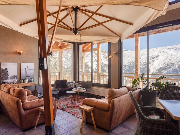 A cozy lounge area with leather sofas, a small table, and a view of snow-covered mountains.