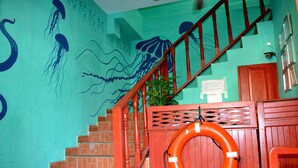 A staircase with a wooden railing and a life preserver hanging on the wall.