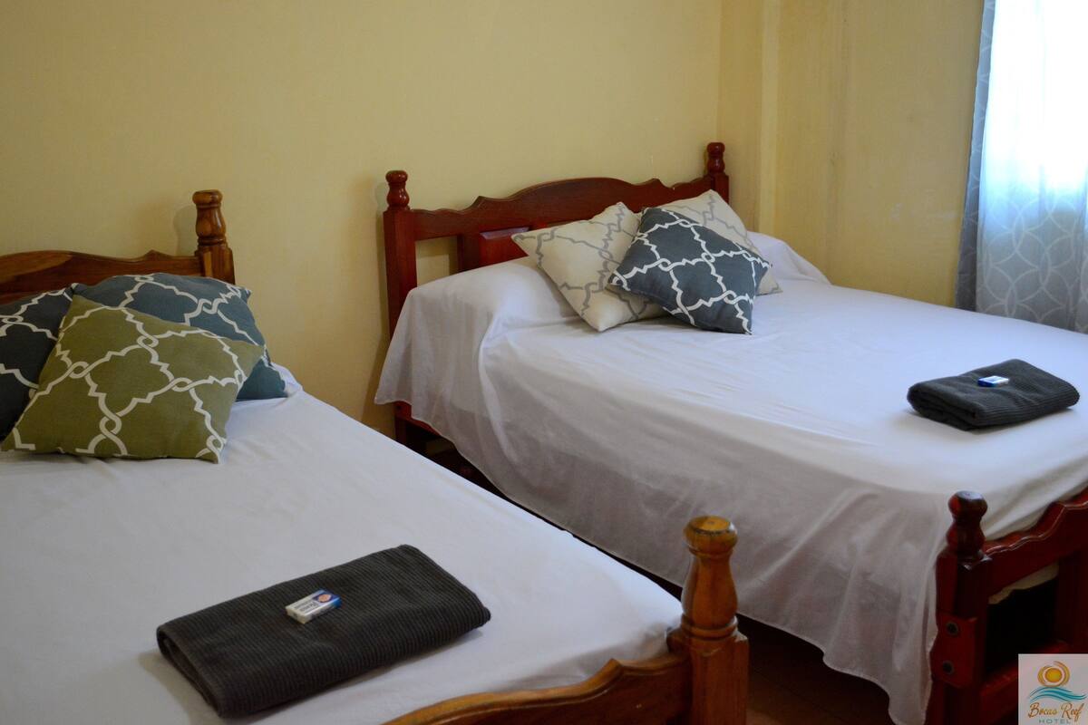 Two single beds with wooden headboards, white linens, and patterned pillows.