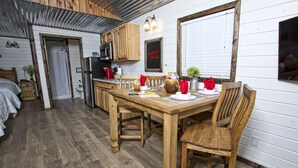 Une cuisine rustique avec des meubles de rangement en bois, une table à manger pour quatre personnes et un réfrigérateur.