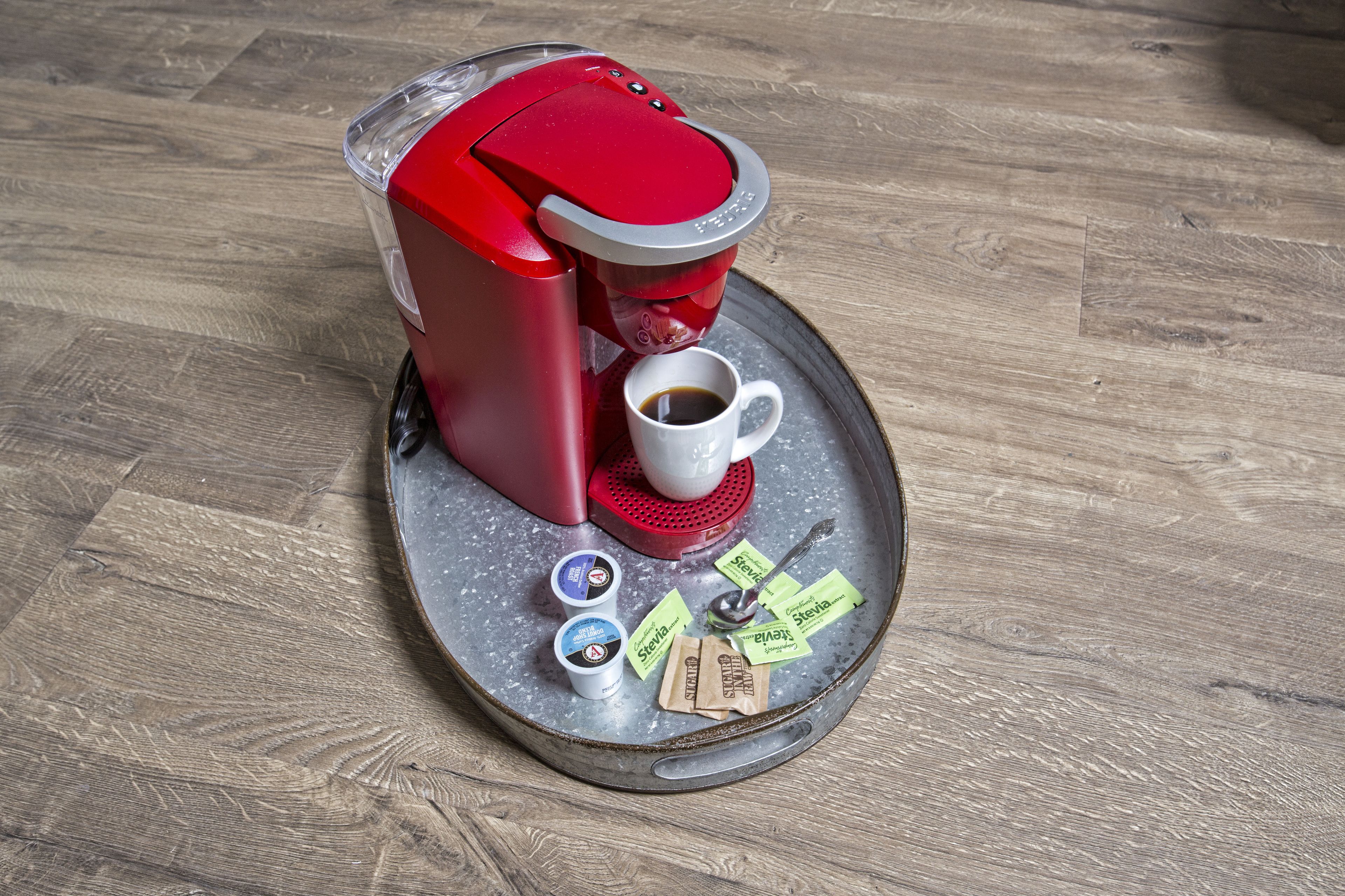 Une machine à café avec une tasse de café et des dosettes de café sur un plateau.