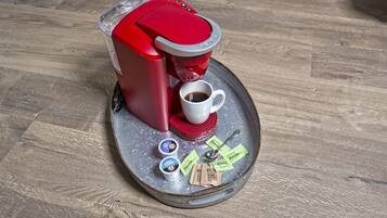 Une machine à café avec une tasse de café et des dosettes de café sur un plateau.