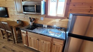 Une cuisine compacte dotée de meubles en bois, d’un four à micro-ondes, d’un réfrigérateur, d’un évier et d’un coin repas avec une table et des chaises.