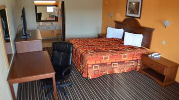 A hotel room with a bed, a desk, a chair, a telephone, and a mirror.