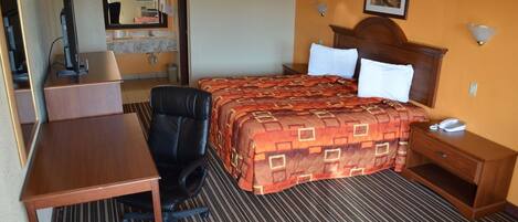 A hotel room with a bed, a desk, a chair, a telephone, and a mirror.