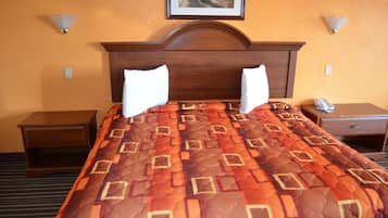 Une chambre d’hôtel avec un grand lit, deux tables de chevet, une petite table et un tableau au mur.