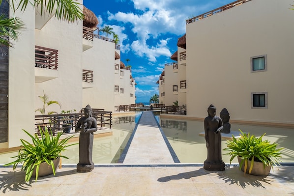 A resort with a central pool flanked by two buildings, each with balconies and potted plants.