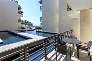Zona de piscina en la azotea con vista al océano, rodeada por una terraza de madera y amueblada con asientos exteriores.
