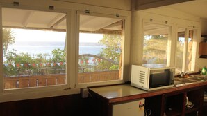 A kitchen with a view of the sea, a microwave, and a refrigerator. - Teukava Beach Oasis (Ha'atafu)