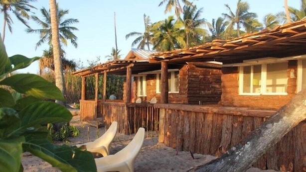 A rustic wooden building with a thatched roof, surrounded by palm trees. - Teukava Beach Oasis (Ha'atafu)