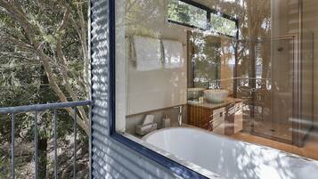 A modern bathroom with a glass shower enclosure, a bathtub, and a visible toilet.