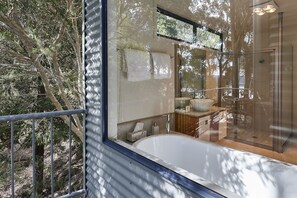A modern bathroom with a glass shower enclosure, a bathtub, and a visible toilet. - Tamar River Apartments (Grindelwald)