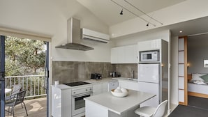 A modern kitchen with a central island, white cabinetry, and a built-in microwave. - Tamar River Apartments (Grindelwald)