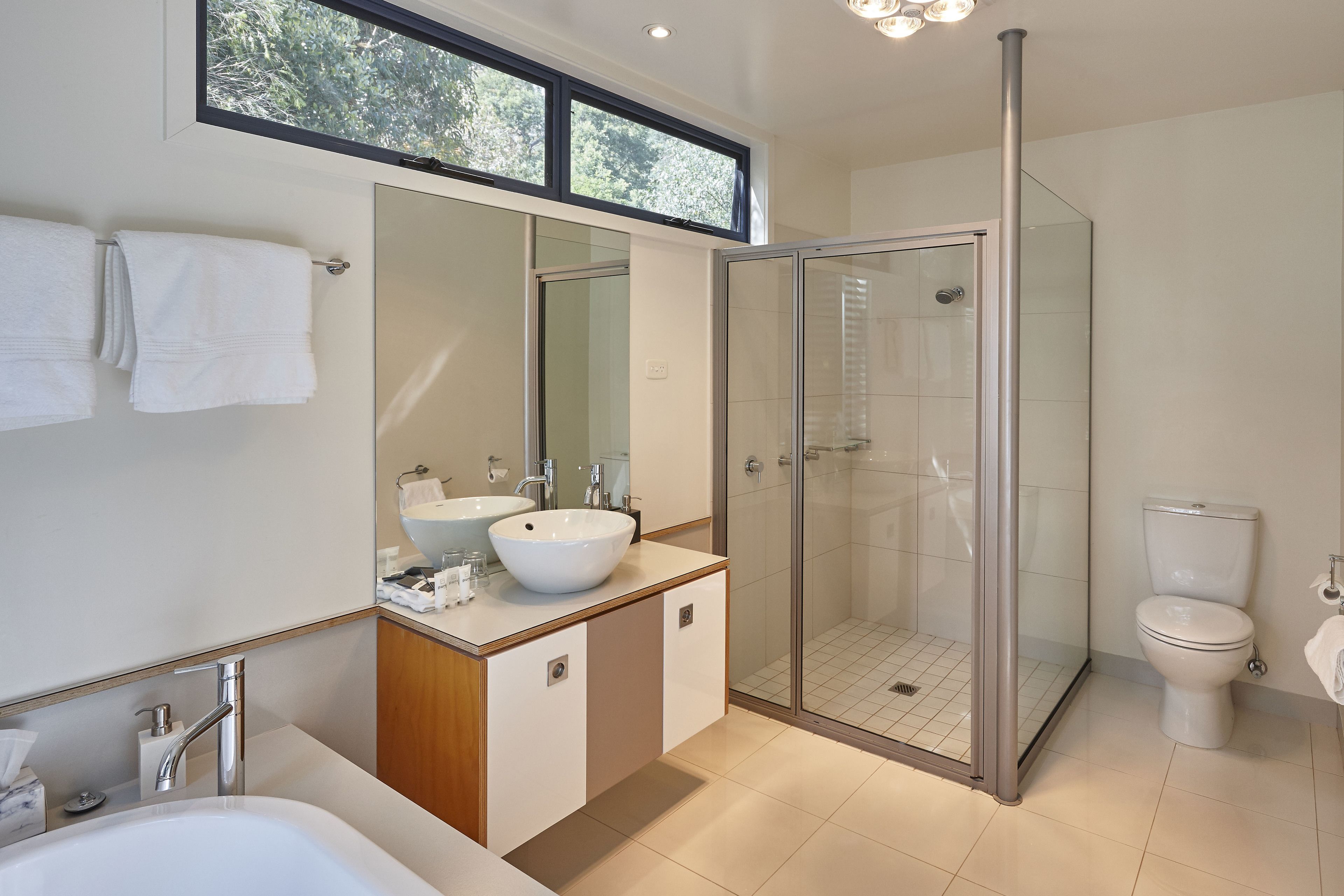 Une salle de bain moderne avec une douche à parois de verre, un grand miroir et une baignoire.
