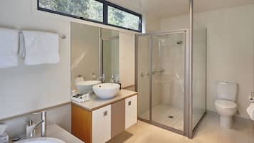 Une salle de bain moderne avec une douche à parois de verre, un grand miroir et une baignoire.