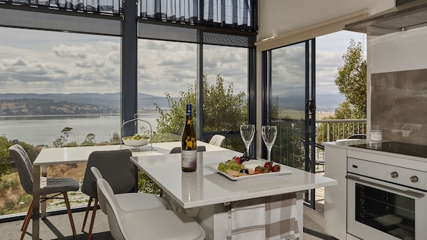 A modern kitchen with a large window overlooking a scenic landscape. - Tamar River Apartments (Grindelwald)