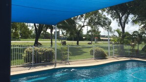 A swimming pool with a white fence and a blue canopy overhead.