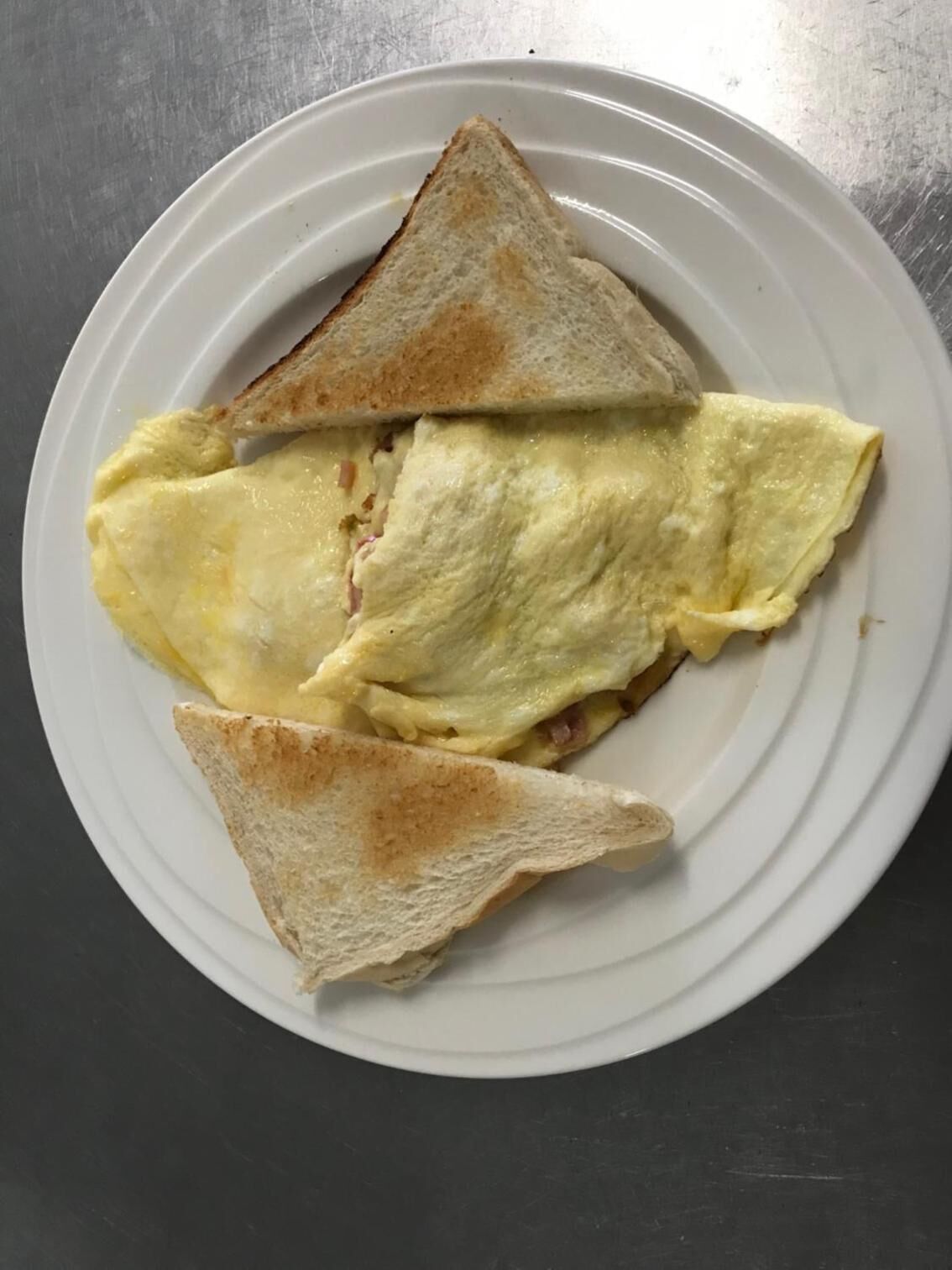Une assiette avec trois tranches de pain grillé et un morceau d’omelette brouillée, le tout servi sur une assiette blanche.