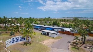 A motel with a sign reading "Motel Bowen Arrow" surrounded by palm trees and a parking area.