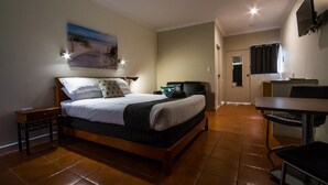 A bedroom with a bed, bedside table, and a desk with a chair.