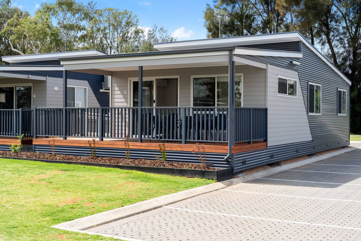 A modern single-story house with a covered porch, a small deck, and a paved driveway.