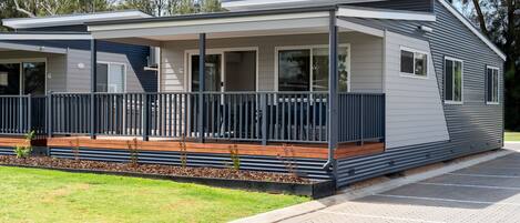 A modern single-story house with a covered porch, a small deck, and a paved driveway.