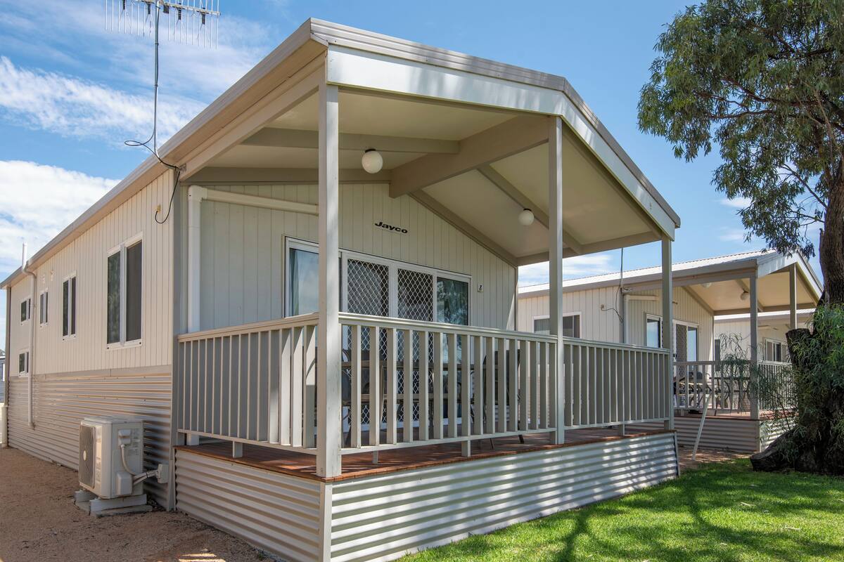 A single-story mobile home with a covered porch and a small deck.