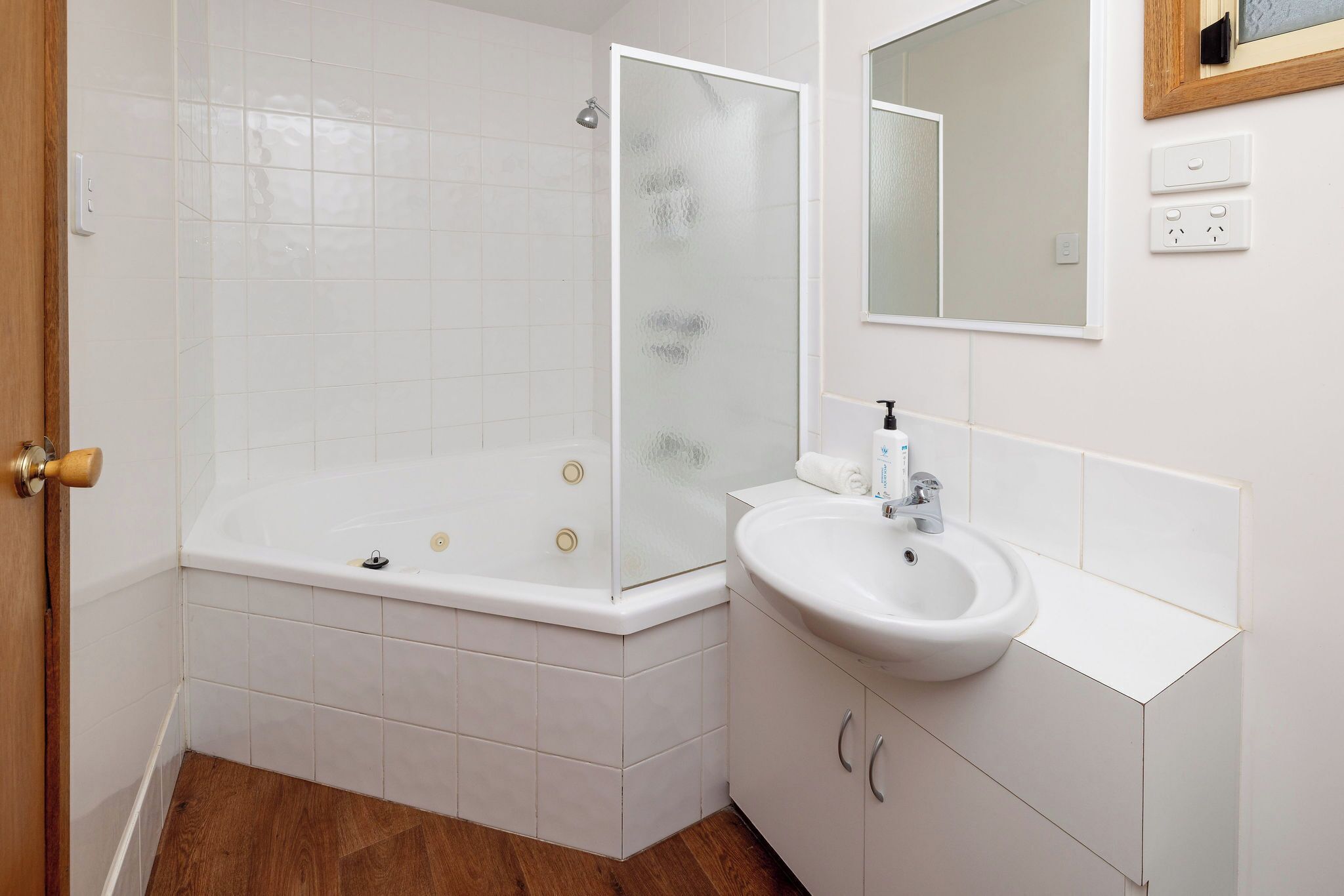 A bathroom with a bathtub, a sink, and a mirror.