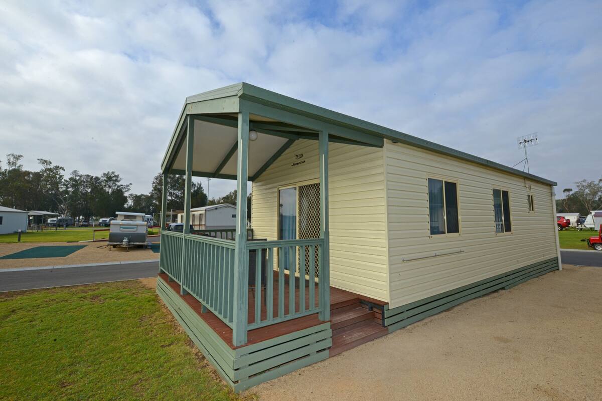 A single-story mobile home with a covered porch and a fenced-in yard.