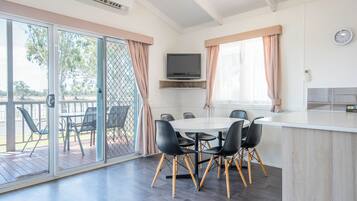 Una cocina moderna con horno integrado, un comedor con mesa redonda y sillas negras, y una puerta corrediza de vidrio que da a un patio exterior.