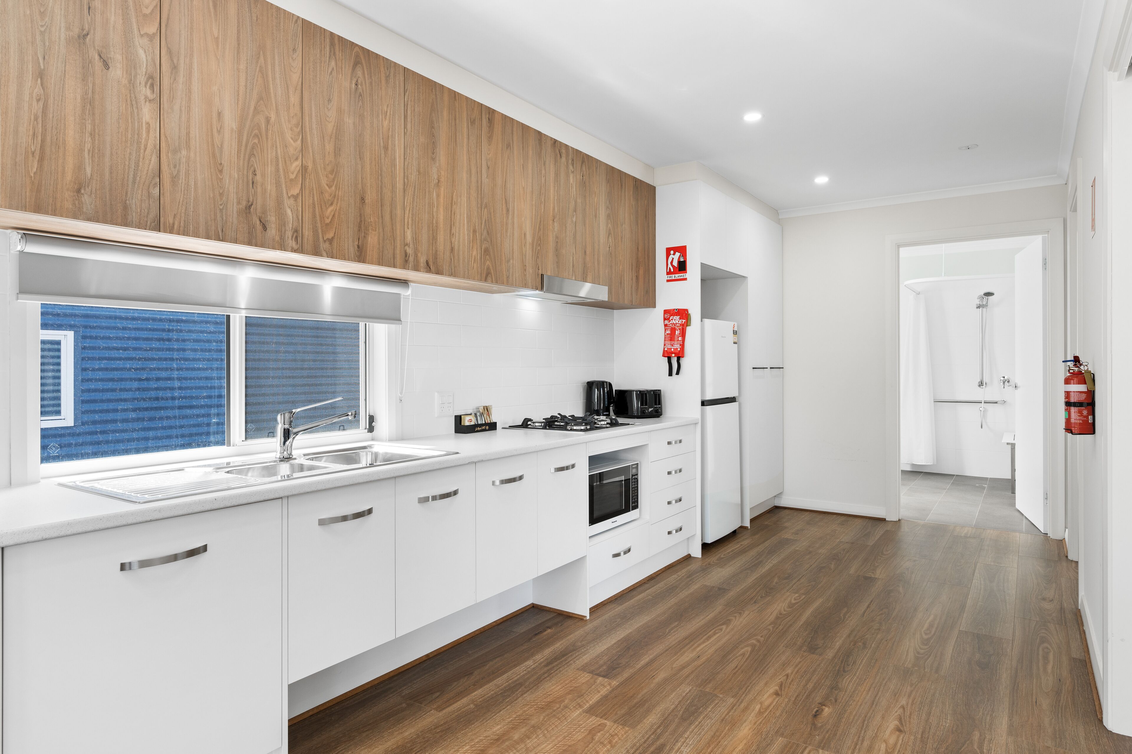 Una cocina moderna con armarios blancos, microondas integrado y pileta de acero inoxidable.