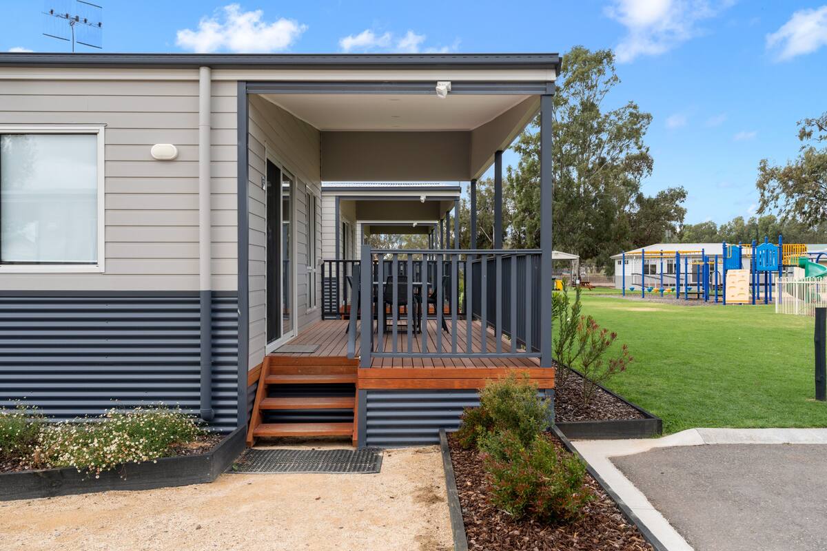 A modern single-story building with a covered porch and a small outdoor seating area.