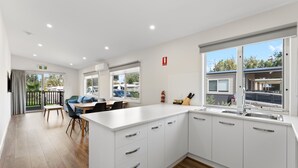 A modern kitchen with white cabinetry, a central island, and a dining area with a table and chairs.