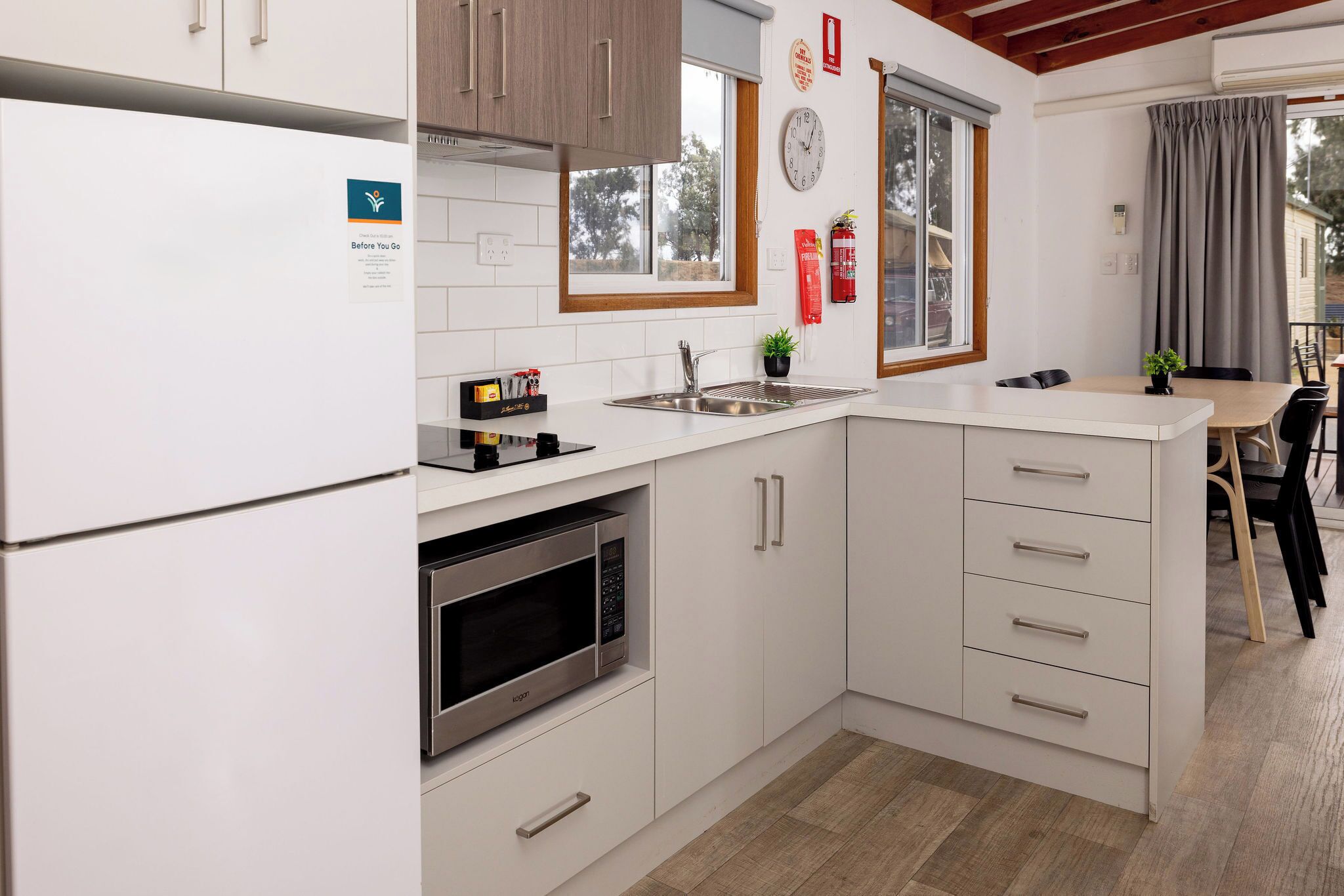 A modern kitchen with white cabinetry, a stainless steel sink, and a built-in oven.