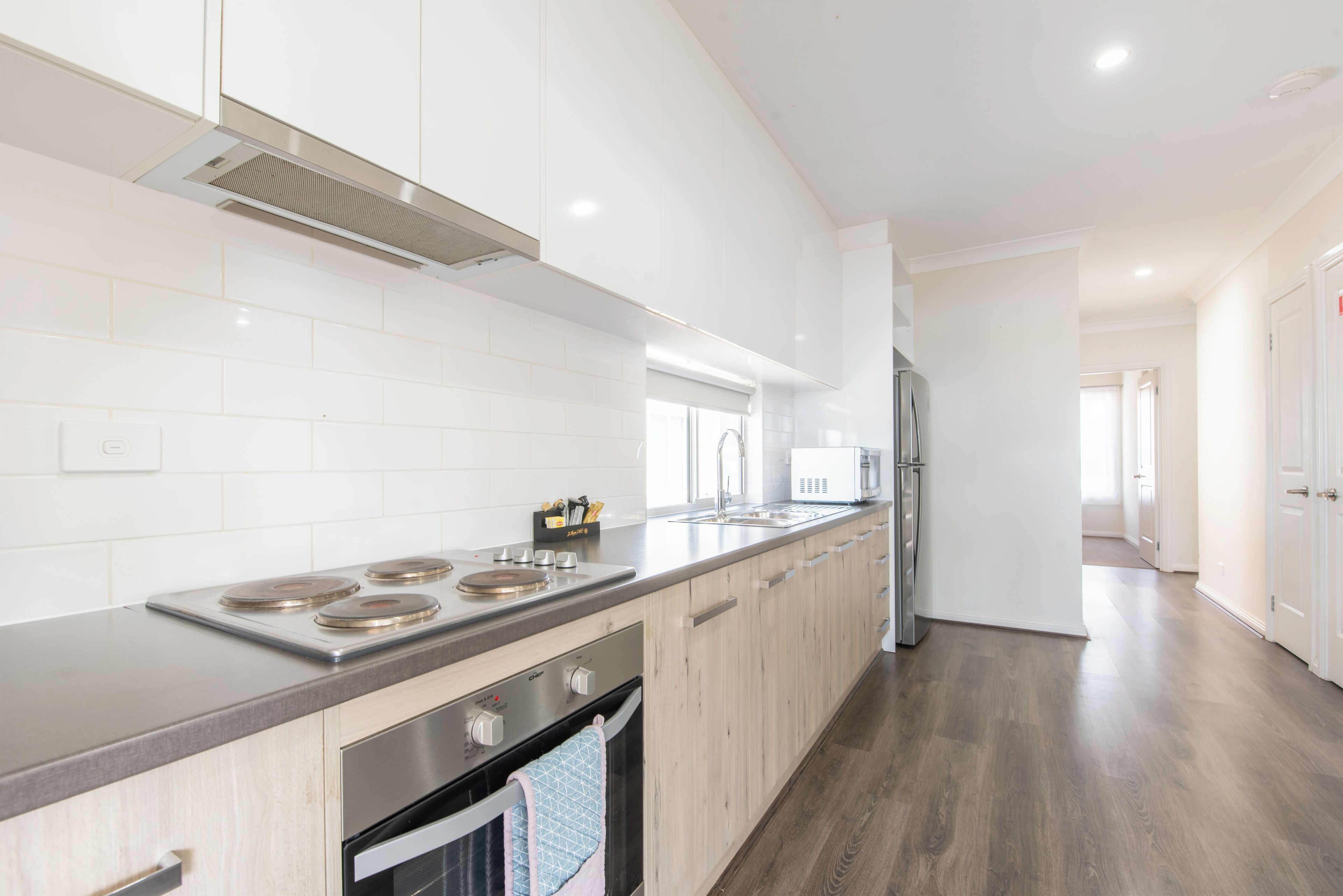 A modern kitchen with white cabinets, stainless steel appliances, and a wooden countertop.