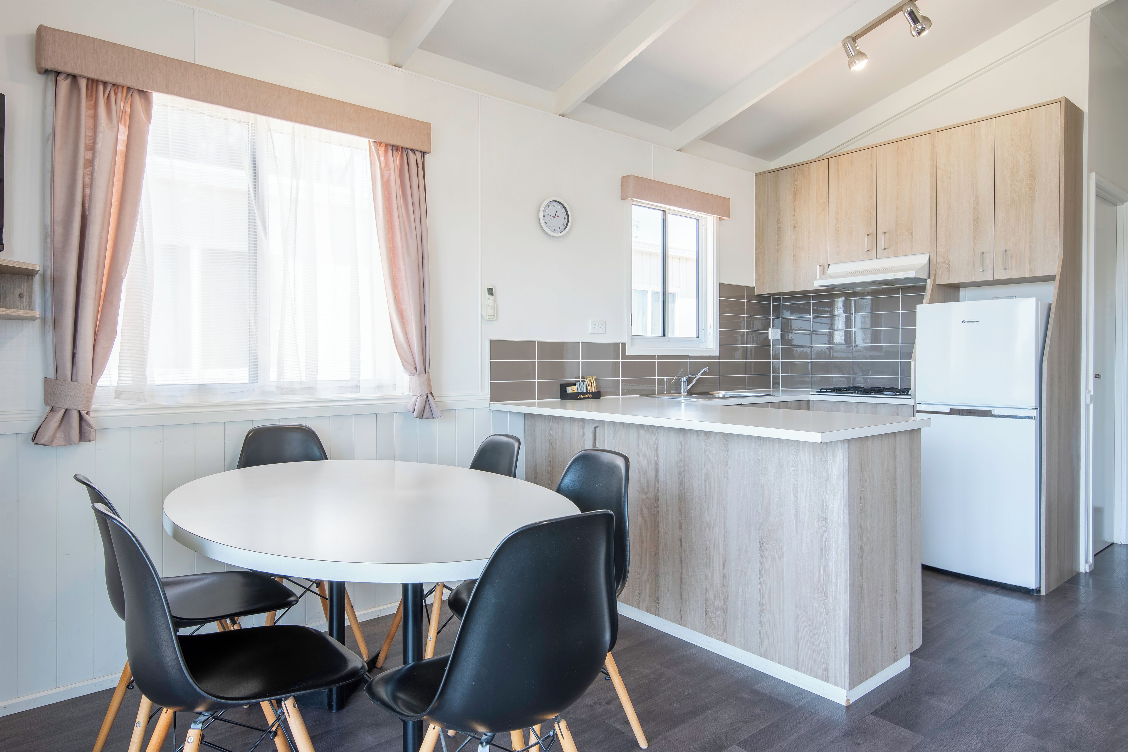 Une cuisine moderne dotée d’un îlot central, d’un coin repas avec une table ronde et des chaises, et de meubles de rangement en bois.