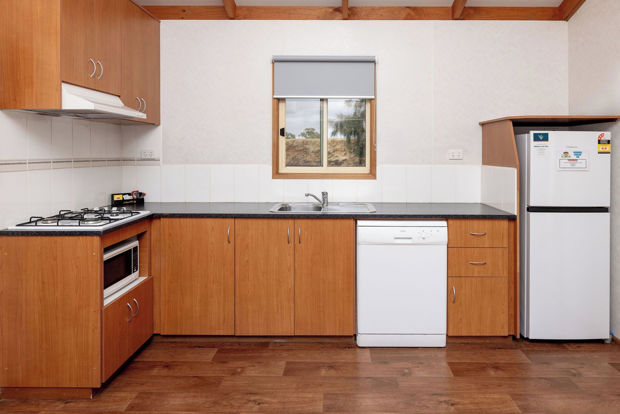 A kitchen with wooden cabinets, a gas stove, a microwave, a dishwasher, and a refrigerator.
