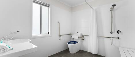 Een moderne badkamer met een witte wasbak, een toilet met een blauwe zitting en een douchegedeelte.