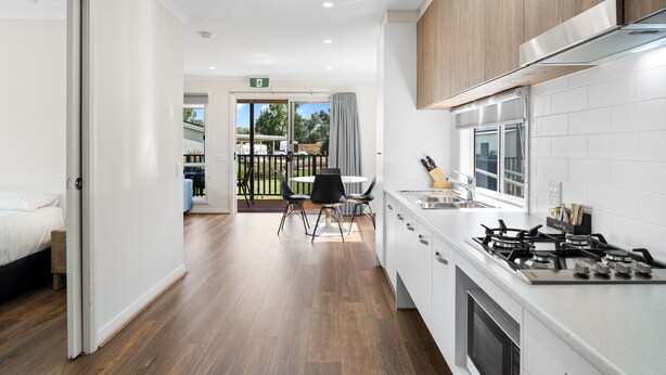 A modern kitchen with white cabinets, a gas stove, and a dining area with a table and chairs.