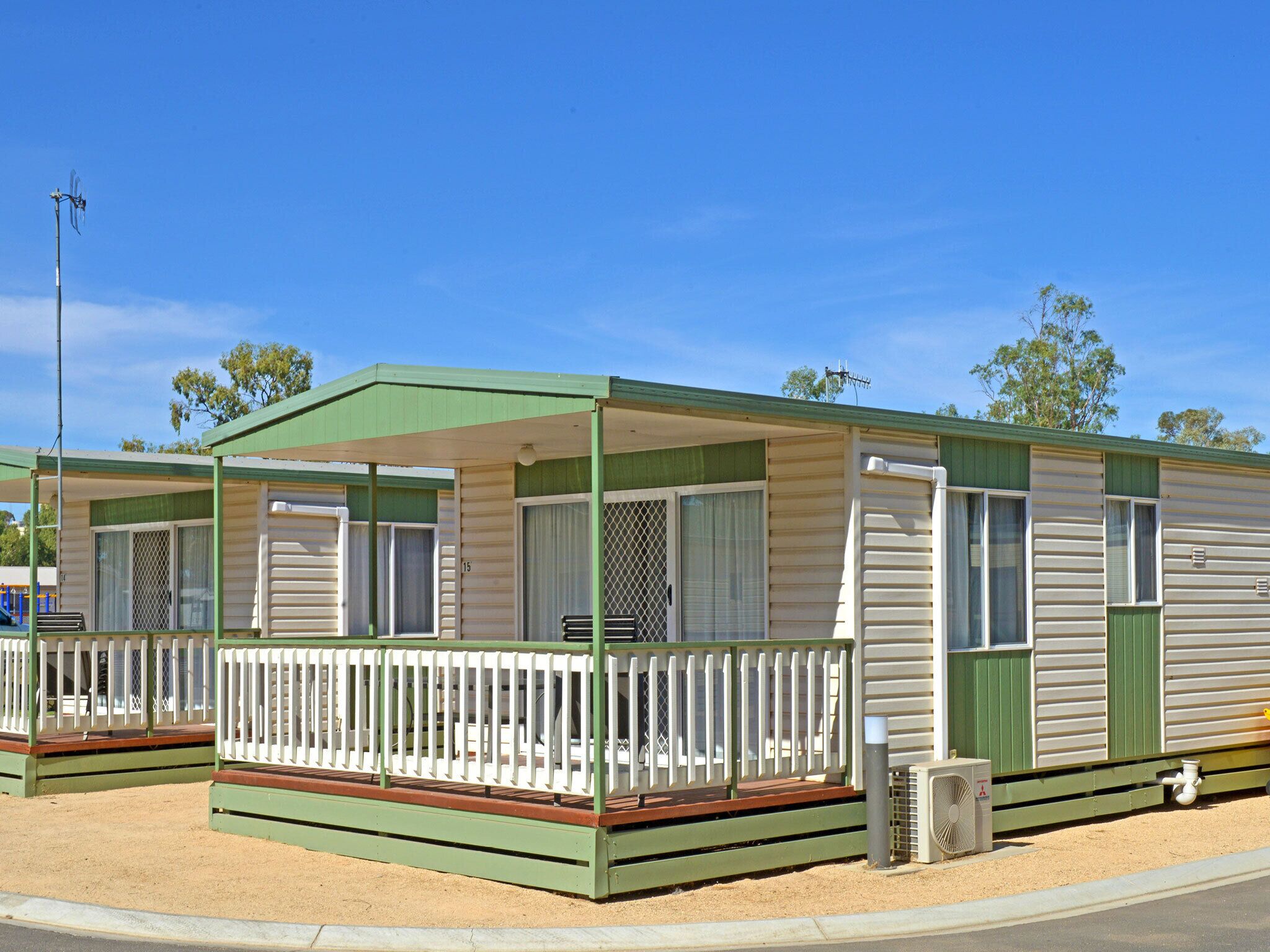 A mobile home with a covered porch, a fenced deck, and a small outdoor area.