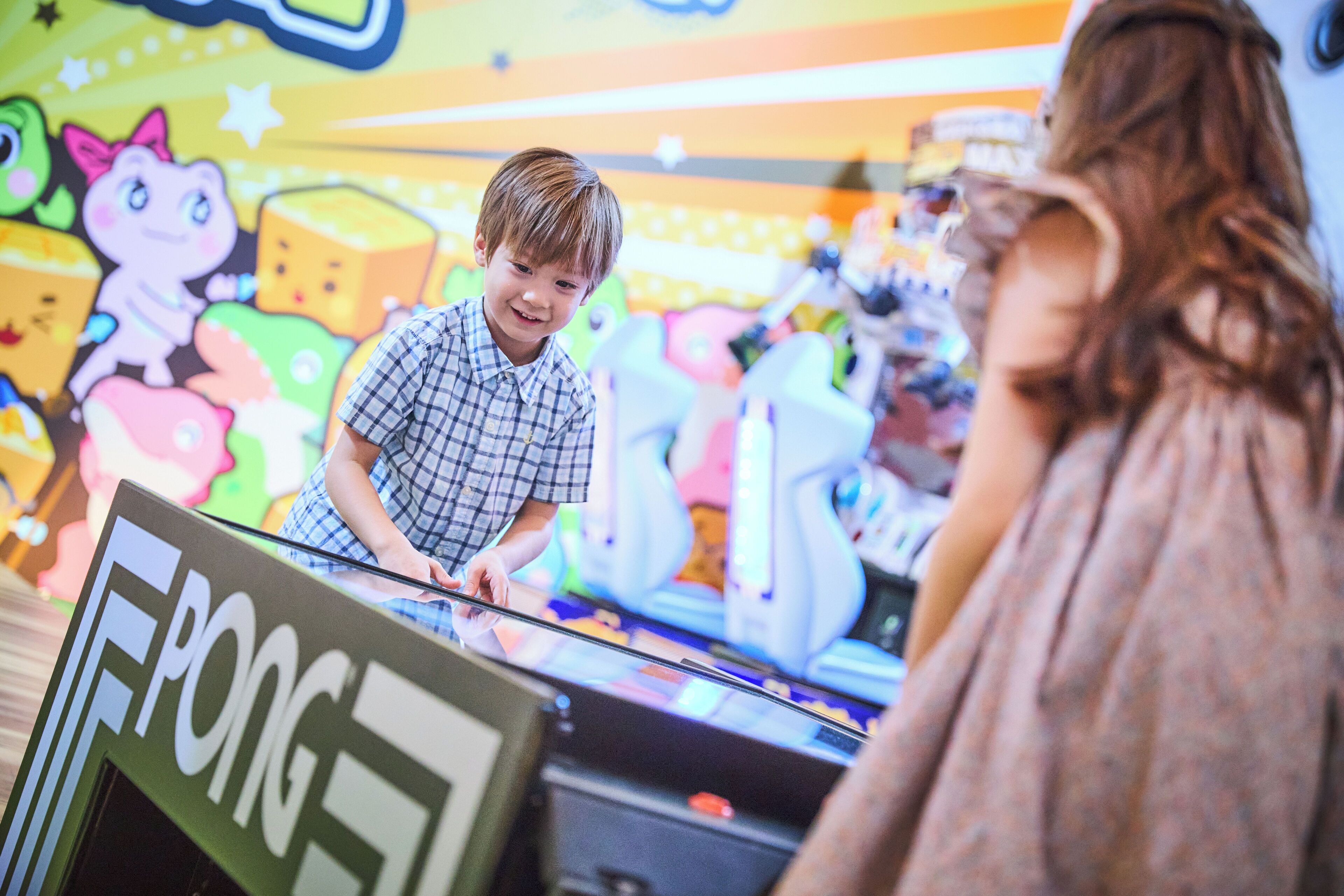 A child playing a game at an arcade with colorful characters on the wall.