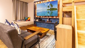 A modern hotel room with a sofa, a coffee table, a TV mounted on a wooden wall, and a bed with curtains. - Hotel Balian Resort Shinjuku Honten (Tokyo)